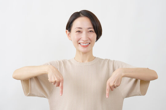 両手で下を指差す笑顔の女性　白背景