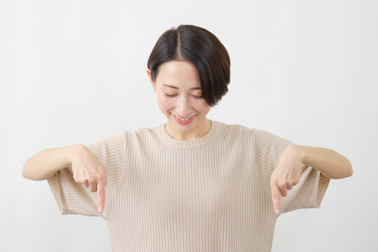 両手で下を指し示す女性　ミドルエイジ　白背.