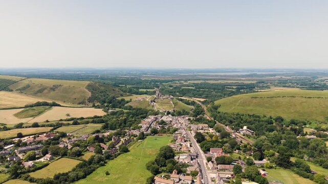 Corfe Isle of Purbeck Dorset, England, forward drone footage over Corfe village with Corfe Castle beyond on sunny Summer day with extensive views of beautiful countryside
