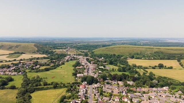 Corfe Isle of Purbeck Dorset, England, high,slow,forward drone footage heading towards Poole harbour over Corfe village with Corfe Castle beyond on sunny Summer day with extensive views