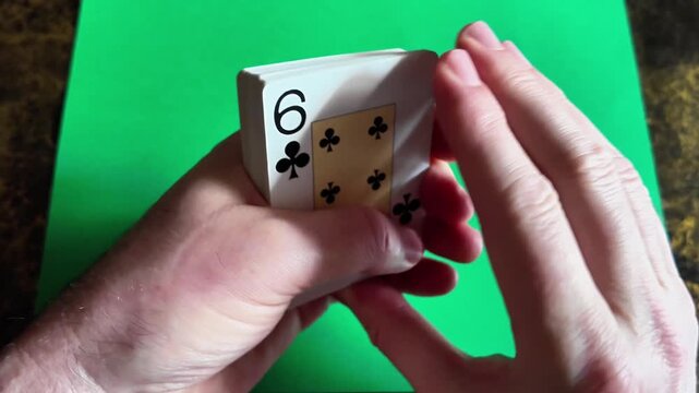 A deck of playing cards moving across a table in slow motion in a close macro view.
