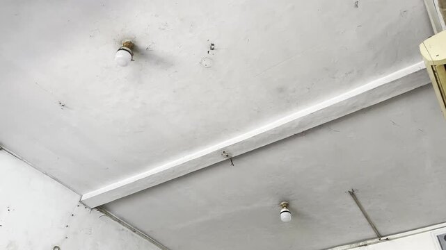 Dirty home ceiling with mold stains and hanging light bulb