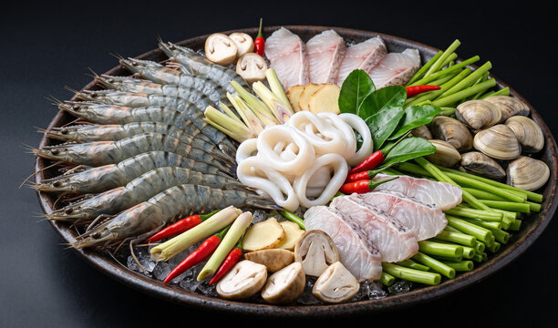 Lau Thai / Lau Hai San (Vietnamese Seafood Hot Pot): An unbaked, artfully arranged platter of fresh seafood for hot pot featuring raw tiger prawns, calamari rings, fish fillets, and clams,