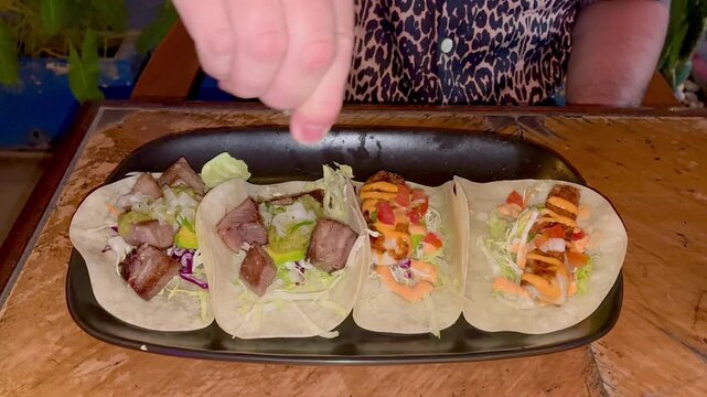 Close up of the man's hand squeezing the lime on top of tacos in Mexican restaurant