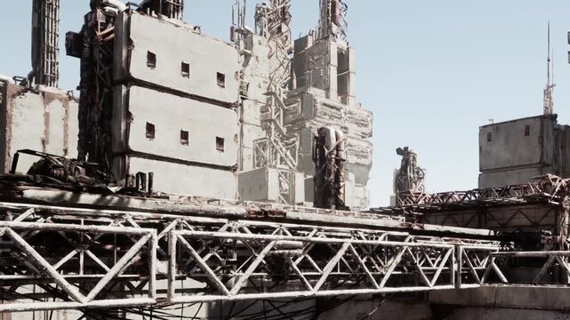 A vast, abandoned industrial complex stands silent under a clear sky. Crumbling structures and rusted machinery tell stories of a once thriving environment now lost to time.