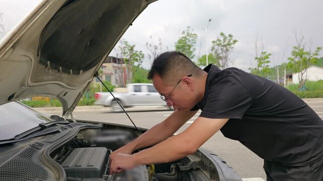 A ham sausage is wrapped in aluminum foil and placed on the engine to heat. The man checks whether the ham sausage has been heated through by the engine.