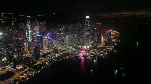 Wide calm night view of the Central and Wan Chai skyline on Hong Kong Island, the tower and tower lit above Victoria Harbour in a steady high aerial hover