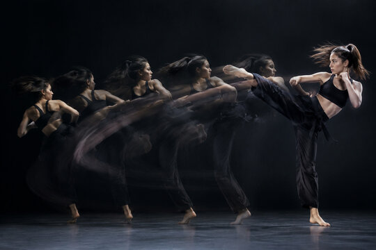 Motion trail of a spinning kick against dark background, capturing fluid movement.