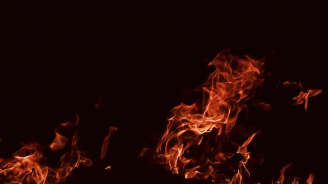 Fire wall with tall twisting flames. Fire closeup with intense orange light. Fire background with layered flame shapes. Big fire.