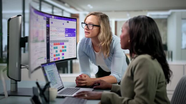 Two Women Managers Discuss Staff Scheduling Using Software Dashboard