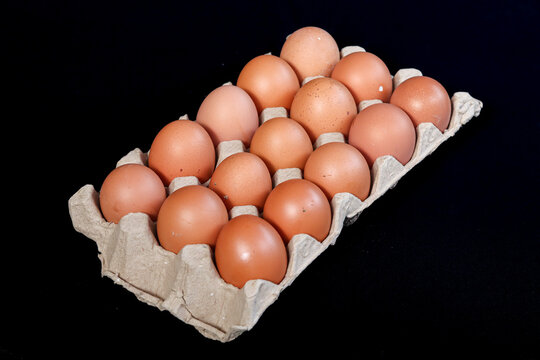 Brown chicken eggs in egg box isolated on black background. Closeup