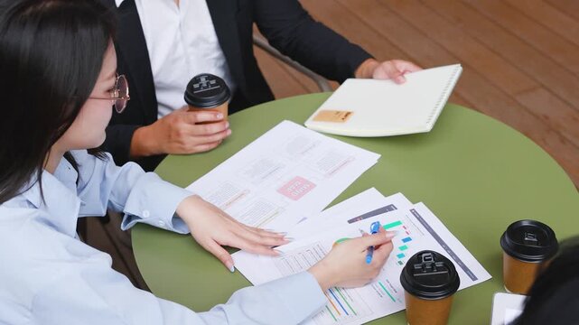 Asian Business Team Reviewing Financial Documents at an Office Table