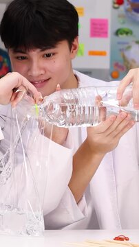 Teenage Student in Lab Coat Pouring Water for Science Experiment