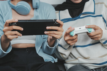 Close up of two young Asian women using console game and joystick, enjoying a shared gaming moment. © ChristyMerry