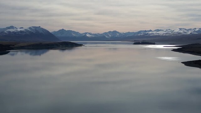 New Zealand aerial view of Lake Pukaki during sunset showcases snow covered Southern Alps mountain scenery with beautiful rugged ranges and peaceful natural landscapes