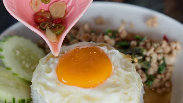Pouring Chili Fish Sauce Over Pad Krapow With Fried Egg