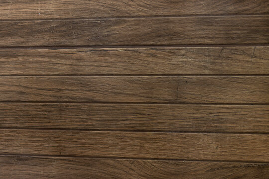 Dark brown wooden planks background texture with horizontal lines, old natural timber surface for design or wallpaper. Detailed warm dark brown tones of a felled tree trunk. Close-up wood texture.