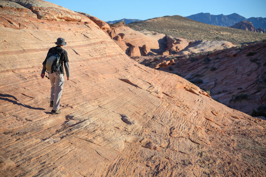 A hiker walking on the colorful sandstone formations of the Fire Wave Trail. Valley of Fire State Park. Nevada, USA.