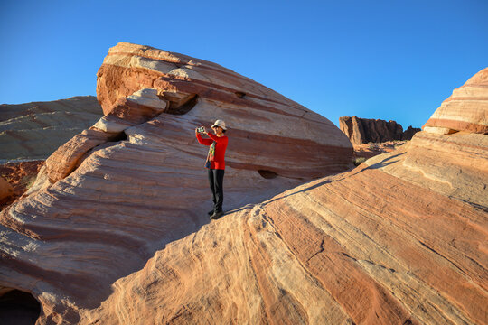 Woman taking smart phone photos at Valley of Fire State Park. Nevada, USA.