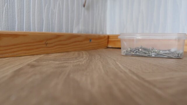 Man Adjusting Baseboard on Floor Installation Video.

