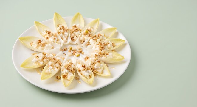 Endive leaves with goat cheese, walnuts, pear and honey on white plate with copy space
