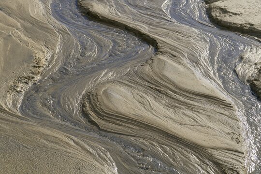 Mud sediment sand silt texture pattern erosion stream mud, sediment, sand, and silt form abstract texture with natural erosion pattern along wet stream channel and rippled surface