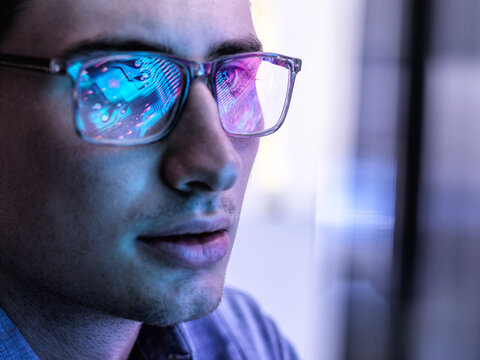 Male electronics engineer is looking at computer chip reflection