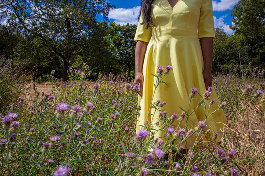 Woman in yellow dress standing in a summer meadow in London