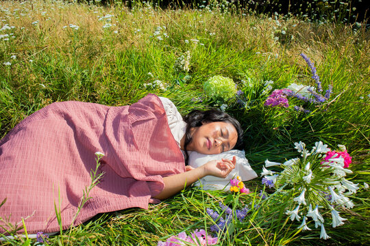 A sleeping woman finds peace under a blanket in a summer meadow