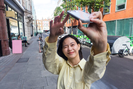 A woman takes a selfie on a London street
