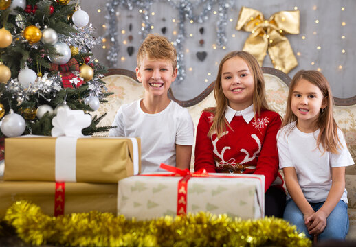 Two girls and boy on sofa in Christmas interior