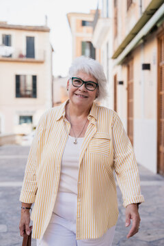 Smiling senior woman walks down a mediterranean street