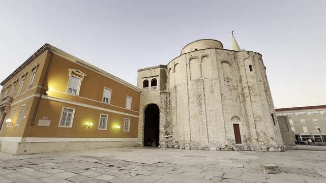 Wide view of historic stone architecture in Zadar, Croatia, featuring an old church and traditional buildings in the city center during evening light.