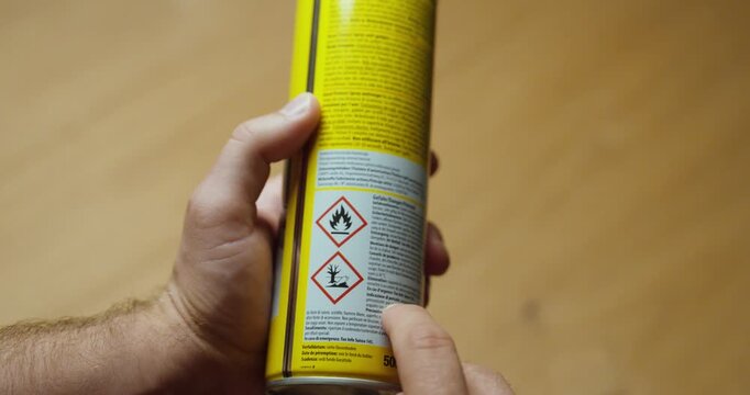 Close-up of hazard warning symbols on an aerosol can, including flammable and environmental hazard pictograms, representing chemical safety, labeling and hazardous materials.