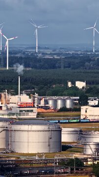 Schwedt Oder, Brandenburg, Germany - PCK Raffinerie GmbH Industrial Complex Featuring a Cooling Tower, Chimney, Storage Tanks, Processing Facilities, and a Wind Turbine - Aerial Drone Shot