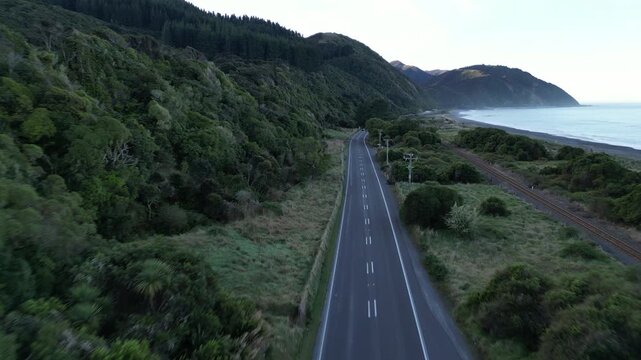 New Zealand aerial view of a coastal road near Ohau Point follows the Pacific Ocean shoreline with rocky coast, crashing waves, mountains and stunning natural scenery 