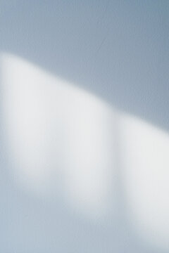 Blue wall background with soft sunlight and diagonal shadow on a textured surface, minimal abstract backdrop with copy space for interior design, product display, branding, banner and mockup.