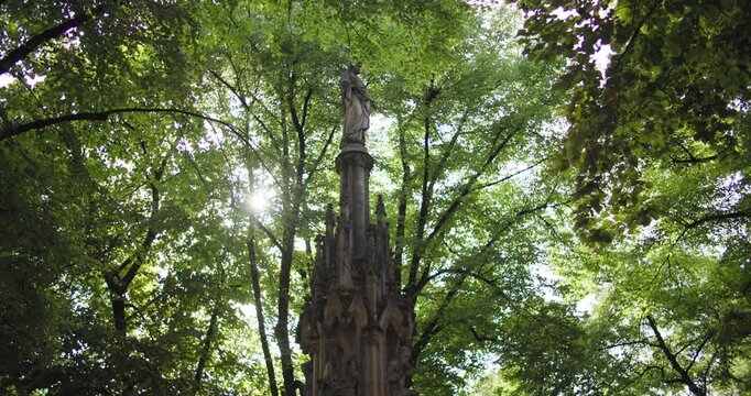 Cologne Germany Mariensaule Marian Column city park captures a historic religious monument among greenery and historic buildings during tourism and travel through Europe.