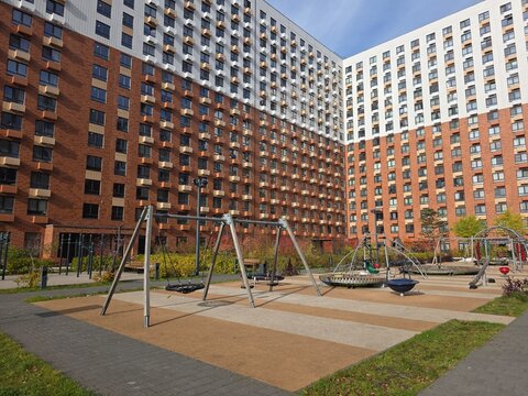 Modern Residential Apartment Complex with Outdoor Playground Contemporary high-rise apartment buildings surrounding a landscaped courtyard with swings and playground equipment, offering recreational 