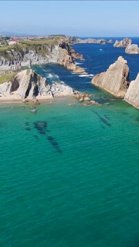 Aerial view of dramatic cliffs, sea stacks, and turquoise water along Costa Quebrada, Cantabria, Spain