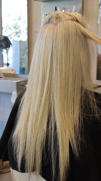 Hairdresser blow-drying long blonde hair with a round brush in a salon