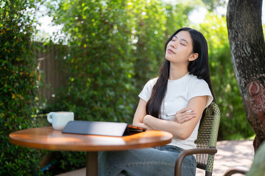 Asian Woman Relaxing with Closed Eyes at Outdoor Workspace