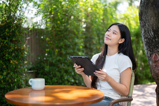 Asian Woman Holding Digital Tablet Looking Up Outdoors