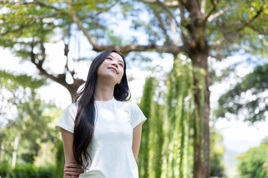 Asian Woman Looking Up with Gentle Smile Outdoors in Nature