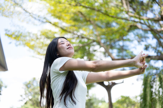 Asian Woman Stretching Arms Forward with Closed Eyes in Nature