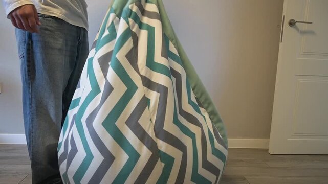 A man standing next to a modern chevron patterned bean bag chair in a room