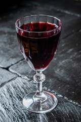 Naklejka premium Elegant red wine served in a detailed crystal glass on a dark stone table