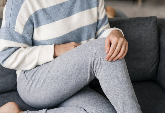 Person sitting comfortably holding knee on grey couch indoors