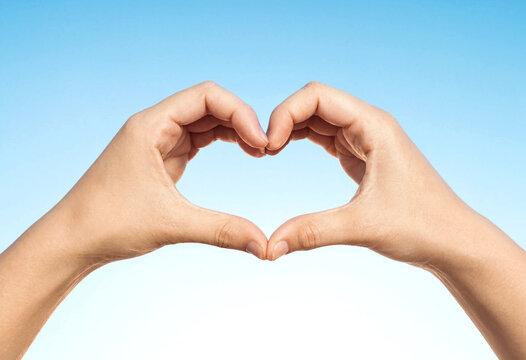 Two hands forming heart shape against clear sky background