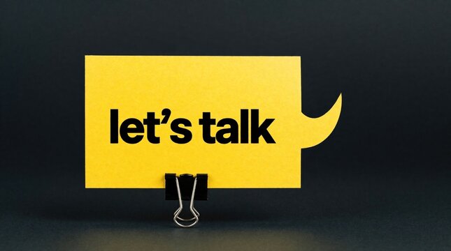 Yellow speech bubble with bold black text lets talk on dark background. Paper note held by black binder clip shows message. Communication concept for social media, business discussion, idea exchange